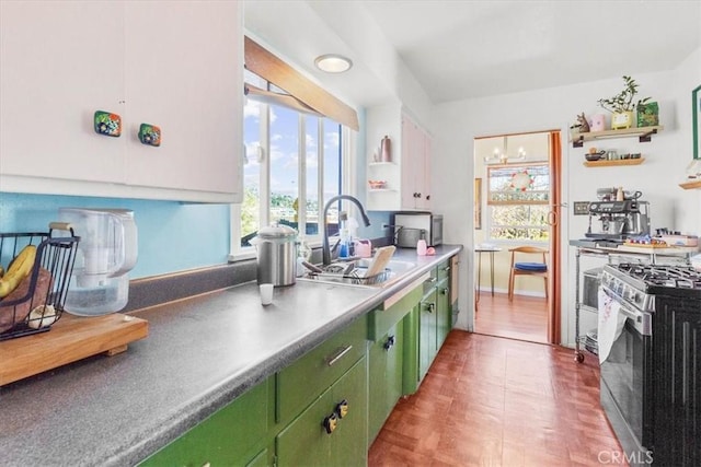 kitchen featuring stainless steel range with gas cooktop, open shelves, a sink, and green cabinetry