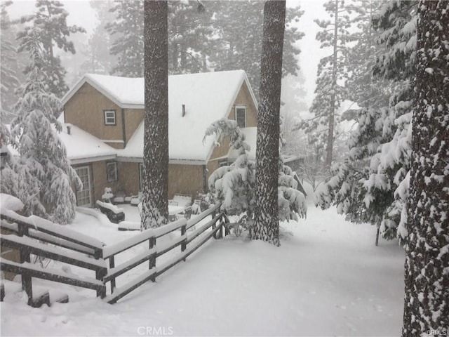 snow covered rear of property featuring fence