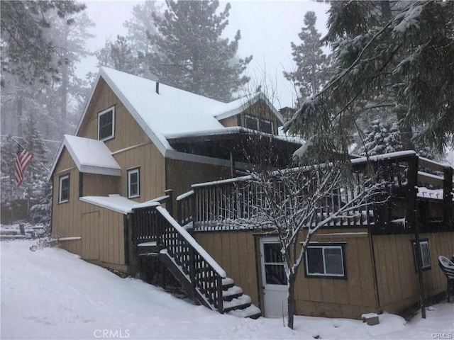 snow covered rear of property featuring stairs