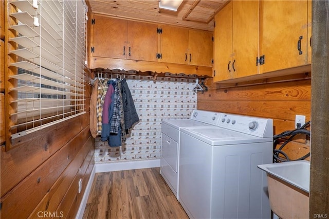 washroom with light wood finished floors, independent washer and dryer, a sink, and cabinet space