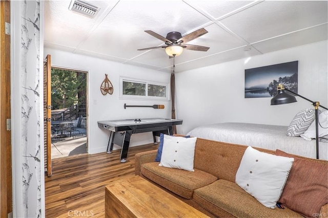 bedroom featuring baseboards, multiple windows, visible vents, and wood finished floors