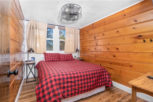 bedroom with wood walls and wood finished floors