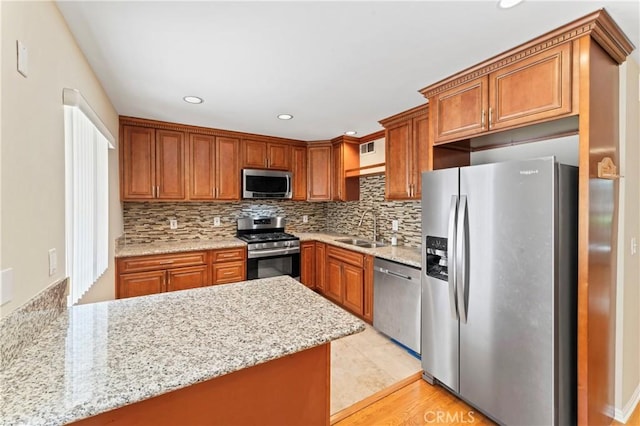 kitchen featuring backsplash, stainless steel appliances, brown cabinets, and a sink