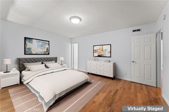 bedroom featuring baseboards, visible vents, and light wood finished floors