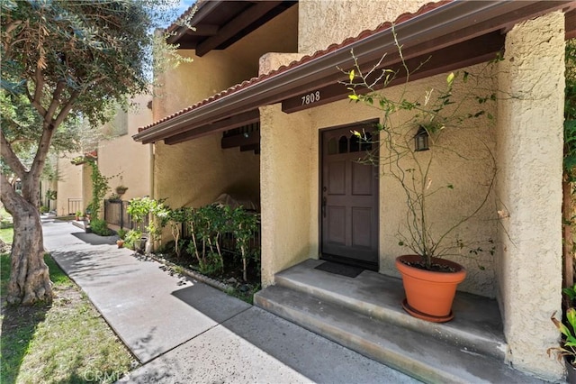 view of exterior entry featuring stucco siding and a tile roof