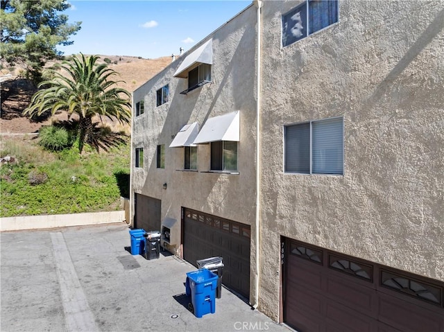 view of side of home featuring an attached garage and stucco siding