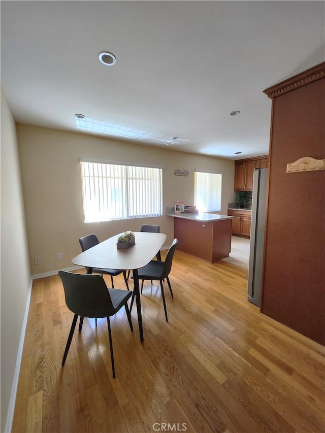 dining space featuring light wood-style flooring and baseboards