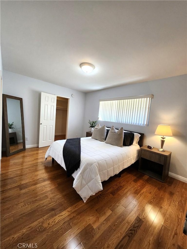 bedroom with wood finished floors, baseboards, and a closet