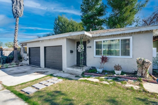 ranch-style home with concrete driveway, a front lawn, an attached garage, and stucco siding