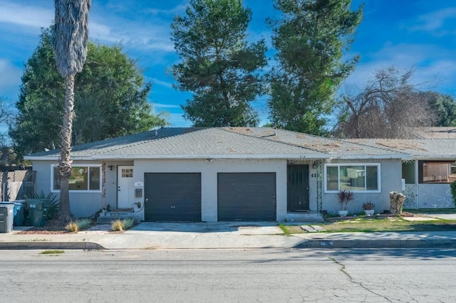 ranch-style home featuring a garage, a shingled roof, concrete driveway, and stucco siding