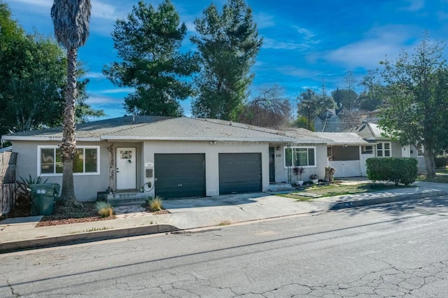 ranch-style home with concrete driveway, an attached garage, and stucco siding