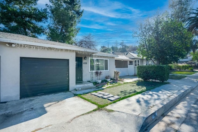 single story home with a garage, driveway, and stucco siding