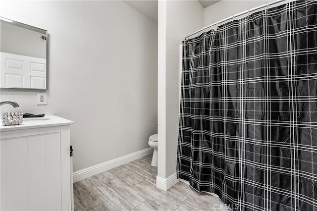 bathroom featuring toilet, baseboards, a shower with shower curtain, and vanity