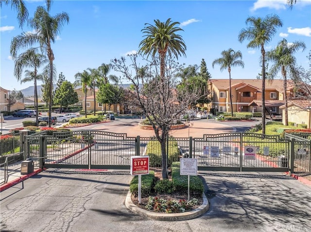 view of road featuring a residential view, a gate, curbs, and a gated entry