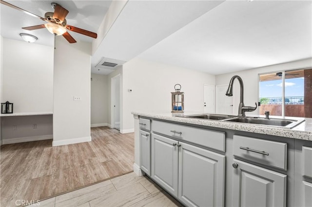 kitchen featuring visible vents, a sink, baseboards, and ceiling fan