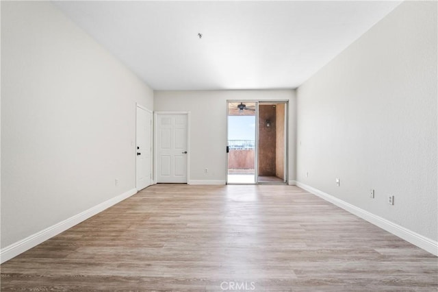 spare room with baseboards, ceiling fan, and light wood-style floors