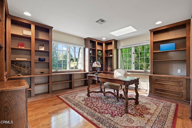 office with a skylight, visible vents, recessed lighting, and wood finished floors