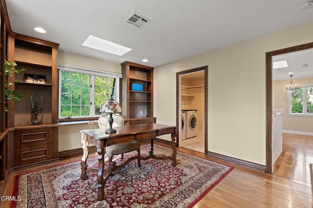 home office featuring a skylight, visible vents, baseboards, light wood finished floors, and washer and clothes dryer