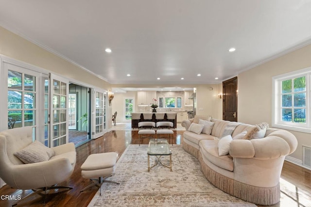 living area with a wealth of natural light, crown molding, recessed lighting, and wood finished floors