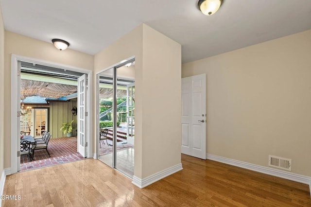 doorway to outside with wood finished floors, visible vents, and baseboards