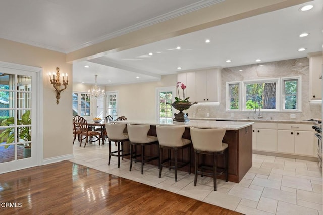 kitchen featuring backsplash, a kitchen island, a sink, and white cabinets