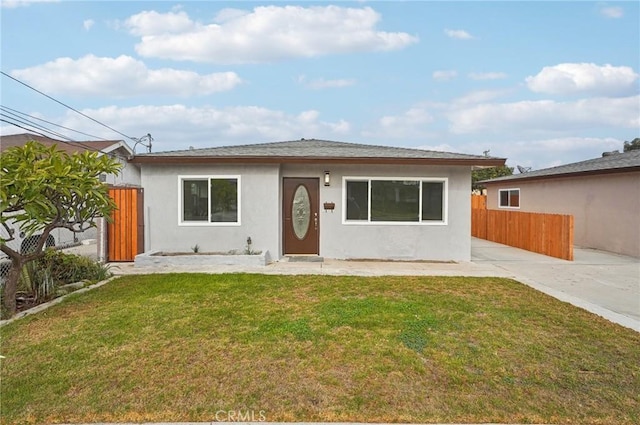 bungalow-style house with fence, a front lawn, and stucco siding