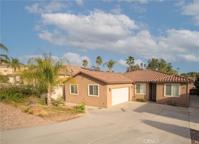 view of front facade featuring stucco siding, a tile roof, fence, concrete driveway, and a garage