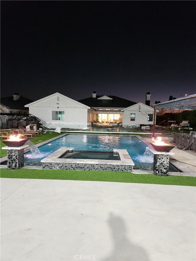 pool at twilight featuring an outdoor fire pit, an outdoor pool, a patio, and an in ground hot tub