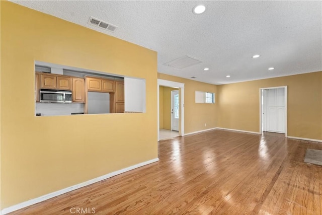 unfurnished living room with visible vents, light wood-style flooring, and baseboards