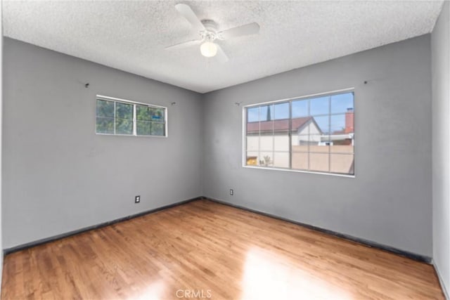 empty room with light wood-style floors, ceiling fan, and a textured ceiling