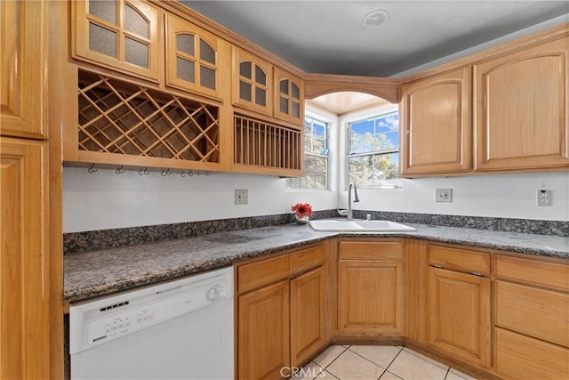 kitchen with glass insert cabinets, dishwasher, a sink, and light tile patterned floors