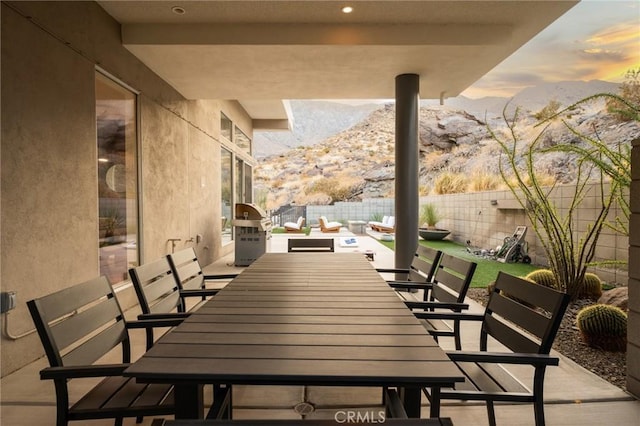 patio terrace at dusk with a fenced backyard, a mountain view, outdoor lounge area, and outdoor dining space