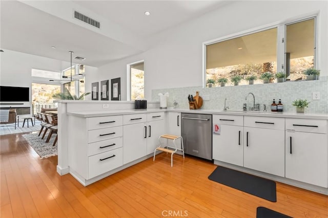 kitchen with light countertops, stainless steel dishwasher, visible vents, and white cabinets