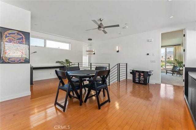 dining room featuring light wood-type flooring, baseboards, and a ceiling fan