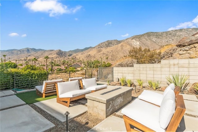 view of patio / terrace featuring an outdoor living space with a fire pit, fence, and a mountain view