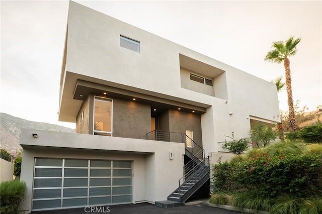 view of front of property with stairs, an attached garage, and stucco siding