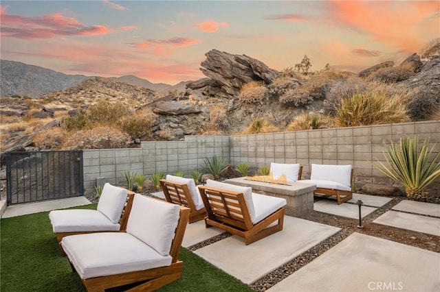 patio terrace at dusk with an outdoor living space with a fire pit, a fenced backyard, and a mountain view