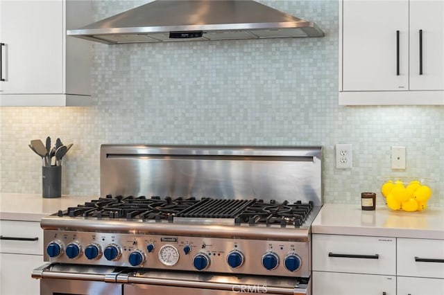 kitchen featuring high end stove, light countertops, exhaust hood, and white cabinetry