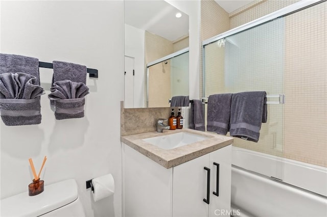 full bath with tasteful backsplash, combined bath / shower with glass door, vanity, and toilet