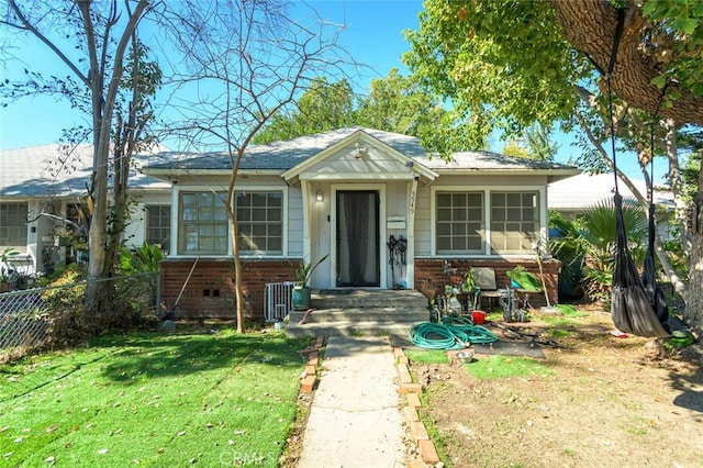 bungalow-style house featuring brick siding, fence, and a front lawn