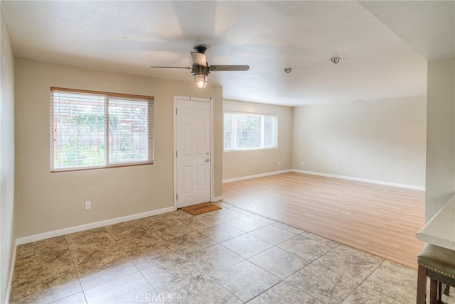 empty room featuring light tile patterned floors, baseboards, and a ceiling fan