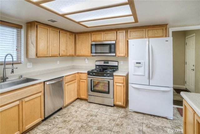 kitchen with visible vents, appliances with stainless steel finishes, light countertops, light brown cabinetry, and a sink