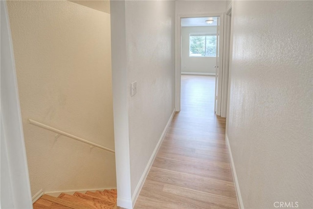 hallway featuring light wood-style flooring and baseboards