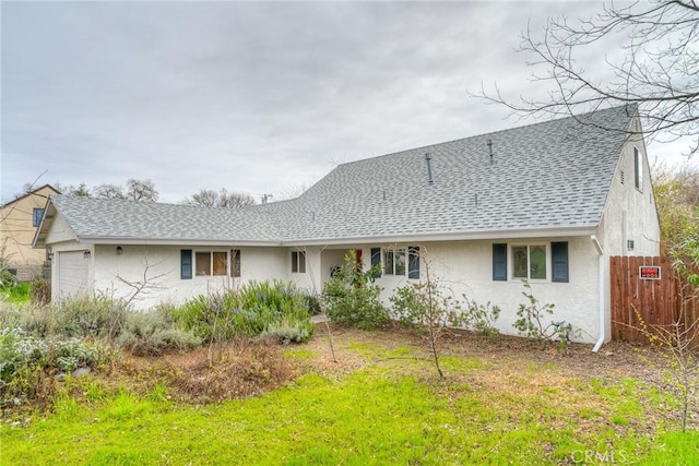 view of front facade with a garage, roof with shingles, fence, and stucco siding