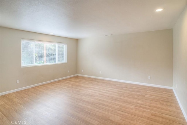 unfurnished room with light wood-style floors, baseboards, and recessed lighting