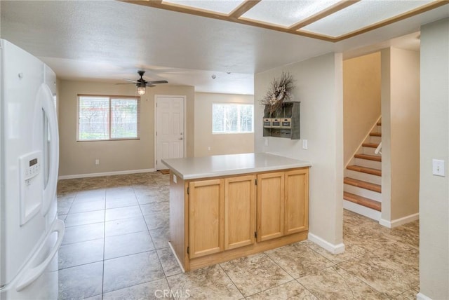 kitchen featuring white refrigerator with ice dispenser, light tile patterned floors, light countertops, light brown cabinetry, and a ceiling fan