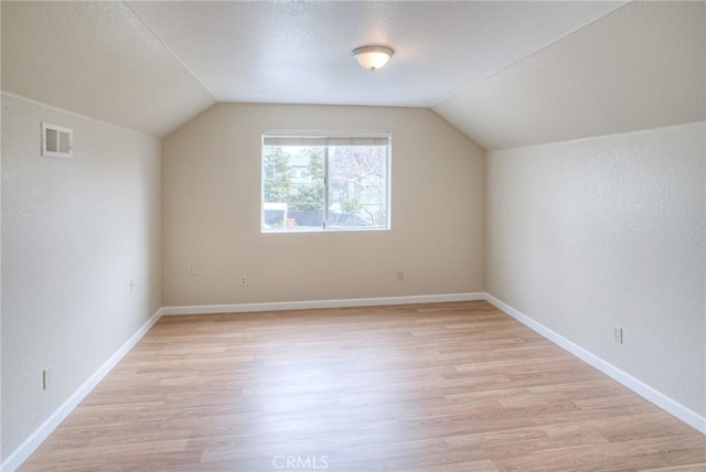 additional living space with lofted ceiling, light wood finished floors, baseboards, and visible vents