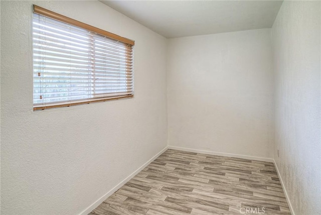 spare room featuring baseboards and wood finished floors