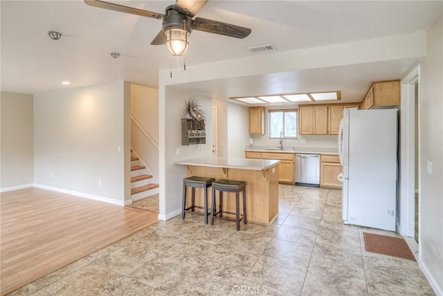 kitchen featuring visible vents, freestanding refrigerator, a peninsula, light countertops, and stainless steel dishwasher