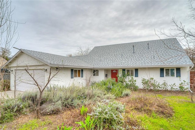 view of front of house featuring a garage, a shingled roof, and stucco siding